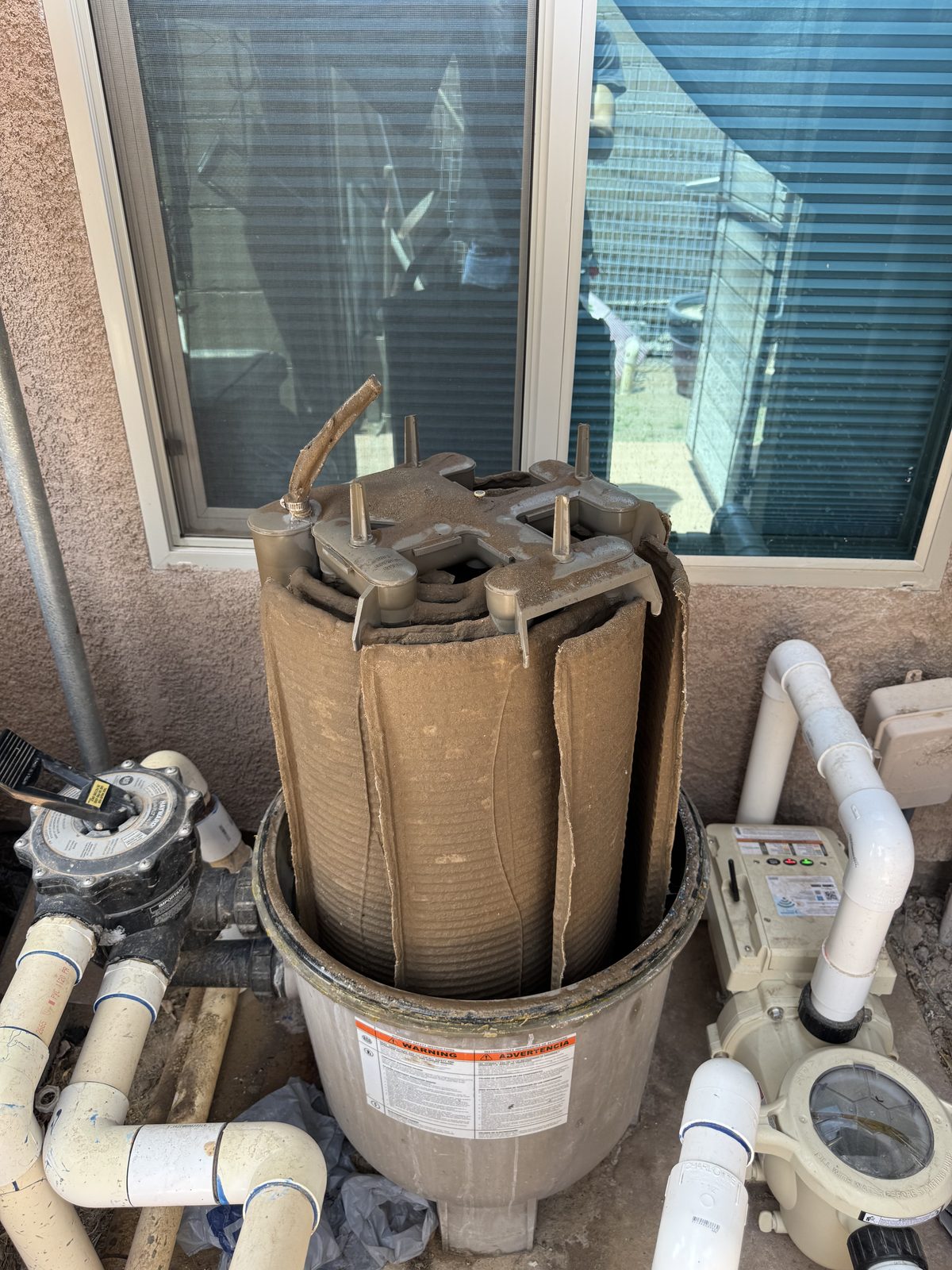 Pool filter cartridge removed for a filter breakdown next to the pump and plumbing at a Yuma home